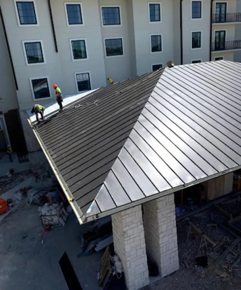 Crew installing standing seam metal roof panels on a commercial project in Malta